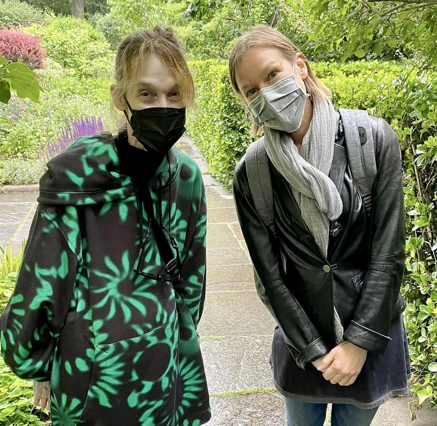 Two women, Robin on the left, Claire on the right, facing the camera, wearing masks (and smiles). Central Park is the backdrop with mostly green foliage, and a footpath stretching behind them.