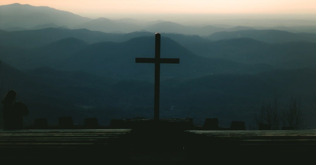 silhouette of cross on top of building during sunset