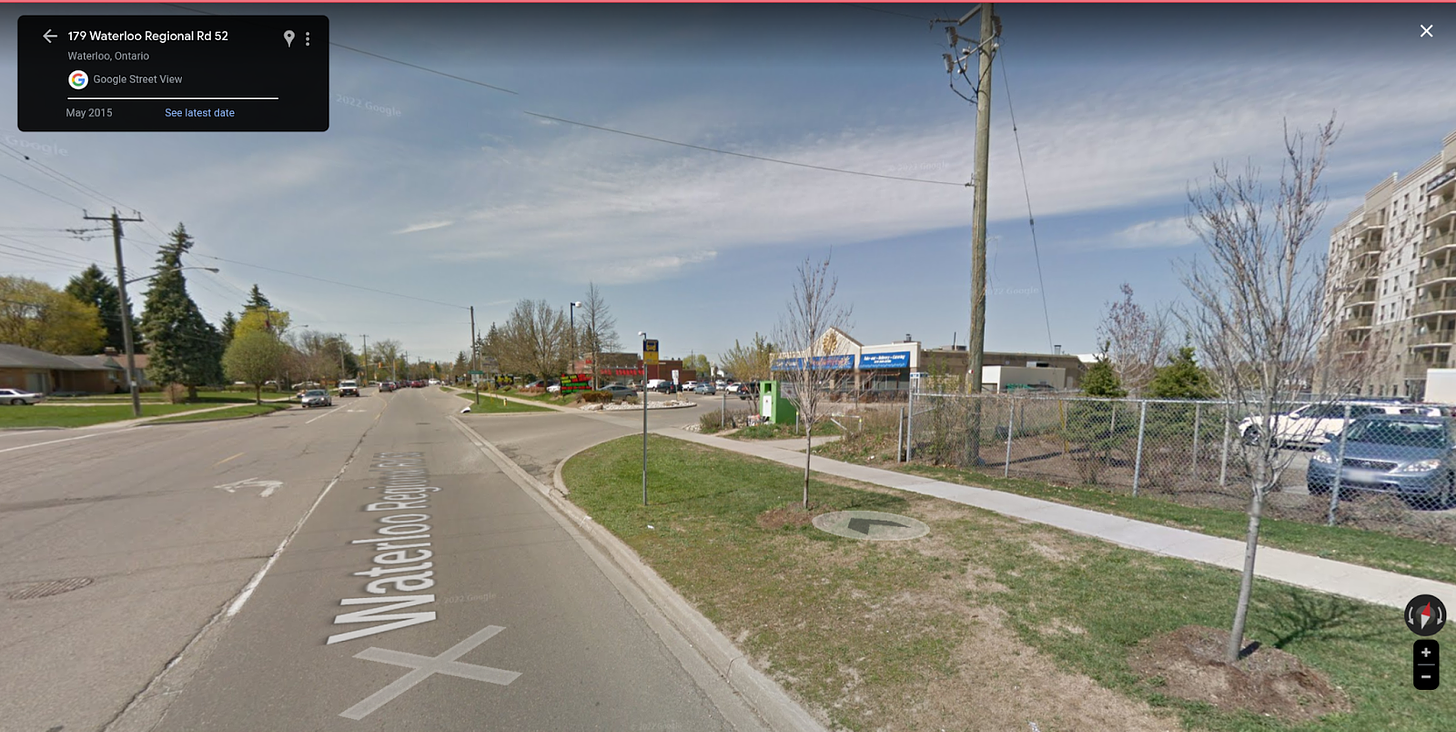 An image of a bus stop in Kitchener, it consists of nothing but a sign on a post in a grassy boulevard.