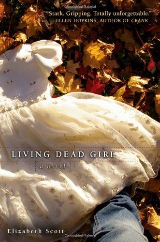 The cover of “Living Dead Girl” which includes a fancy white  little girl’s dress with white ribbon roses and white embroidery. This is on red and yellow leaves on the ground. At the edge is the bottom half of waht appears to be a man’s leg in jeans.