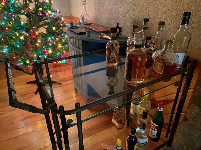 glass drink cart with liquor bottles next to a christmas tree