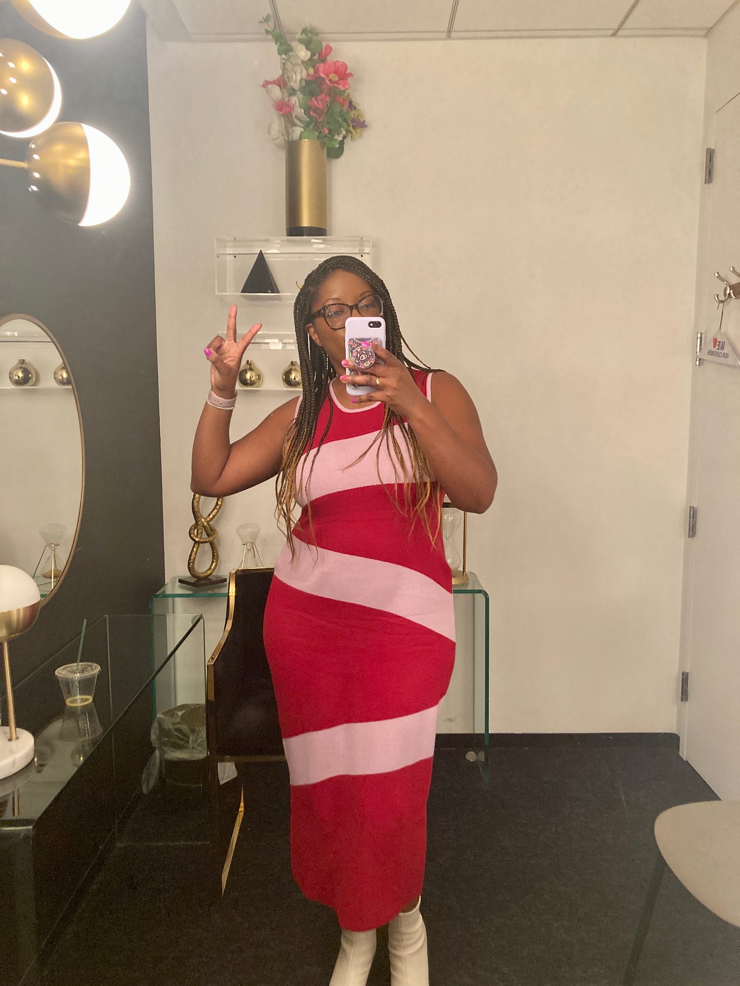 Picture of a Black woman wearing a pink and red dress standing in front of a mirror