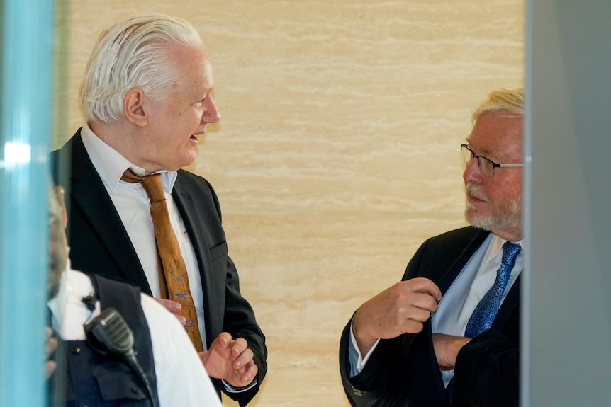 A side shot of two men wearing suits in a conversation with each other