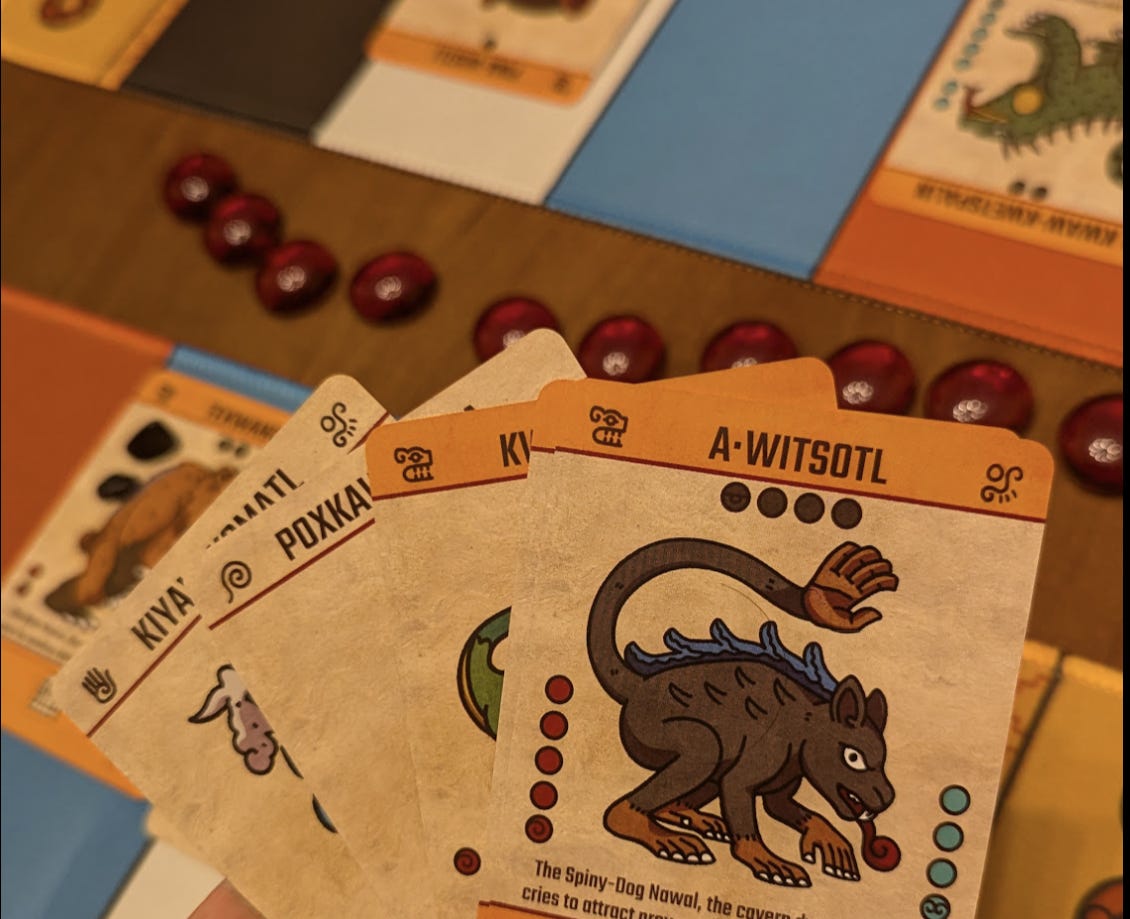 Cards of the board game NAWALLI, with hand-drawn creatures in an Aztec style. Table and red glass stones in the background.