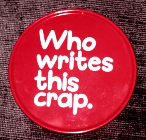 A red coaster with white lettering. "Who Writes This Crap."