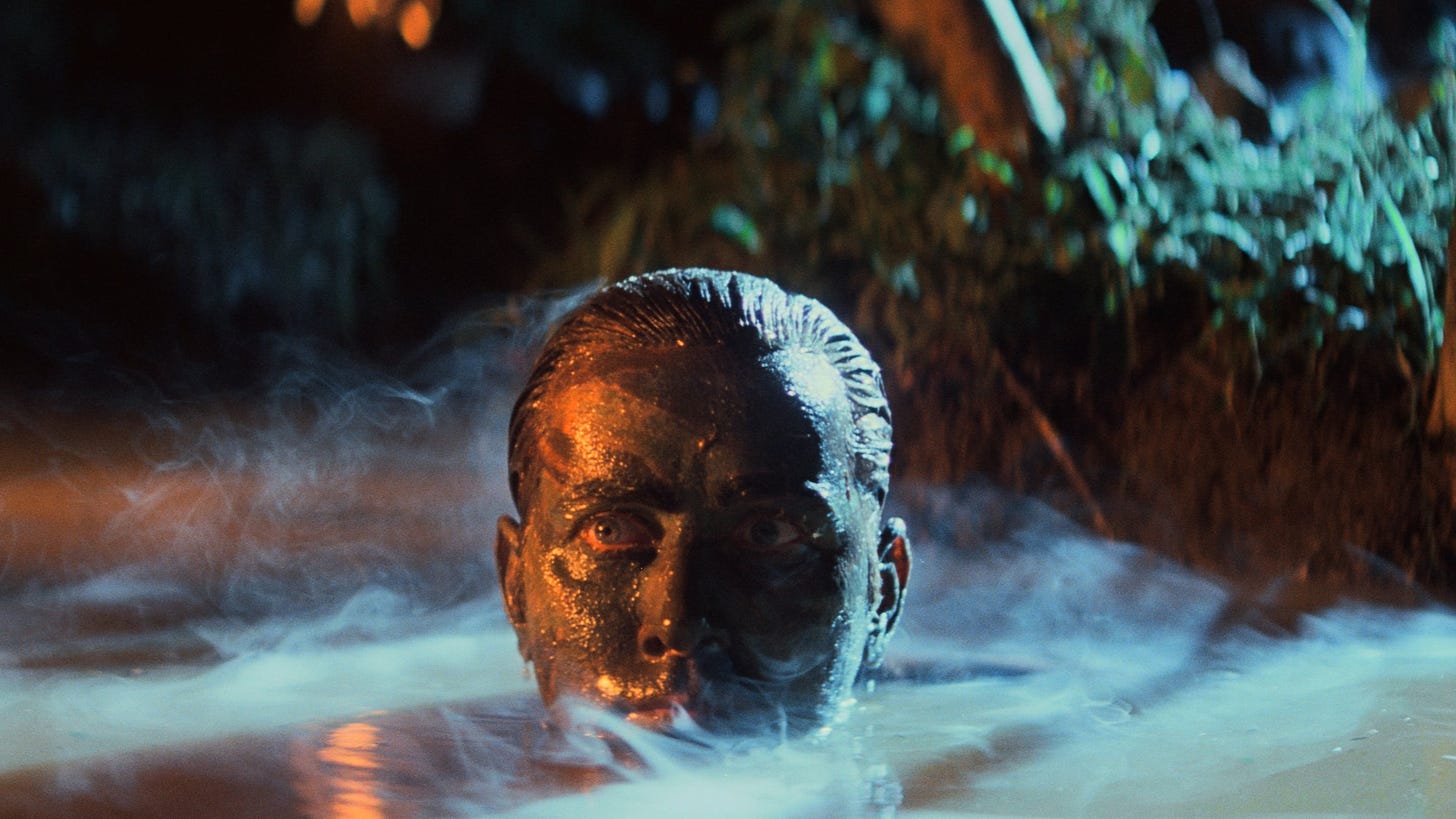 A still from Apocalypse Now featuring Martin Sheen rising from the water with green face paint.