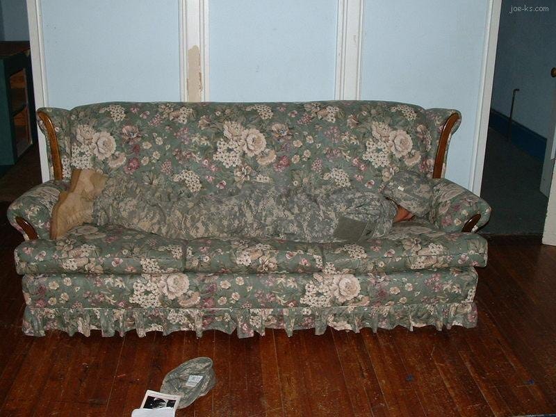 A US army soldier wearing ACU camo (retired by the Multicam camo pattern)  hides on a couch, making him hard to see. We pretend the vaccine did this, as a joke. 