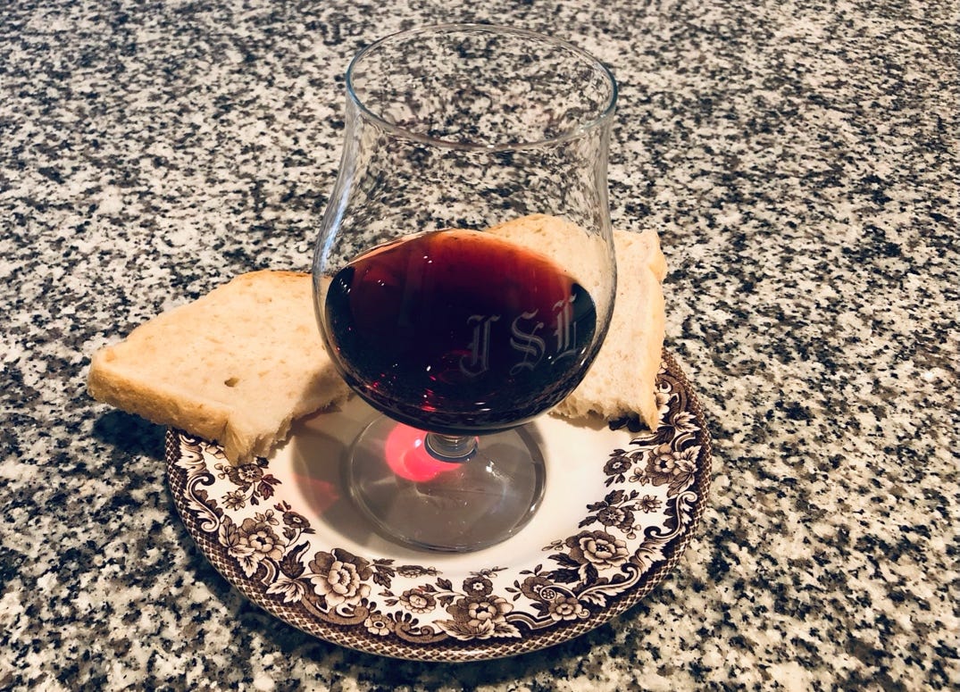 A glass of wine and bread on a plate

Description automatically generated