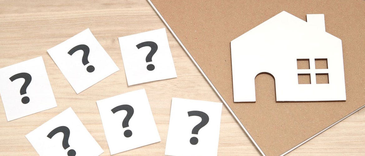 6 questions marks on cards next to a flat white house