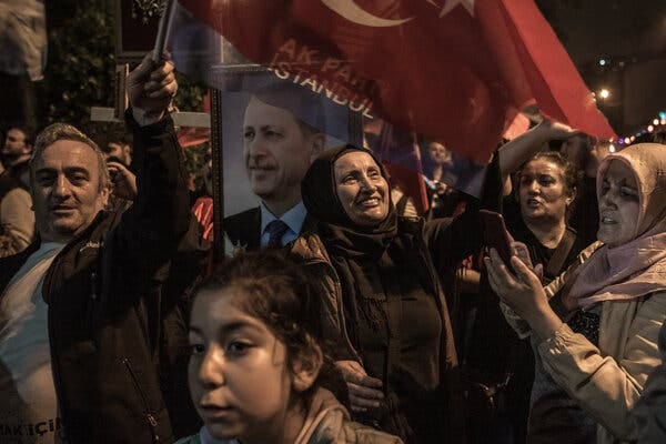 A crowd of Turks holding a flag and a portrait of their president.