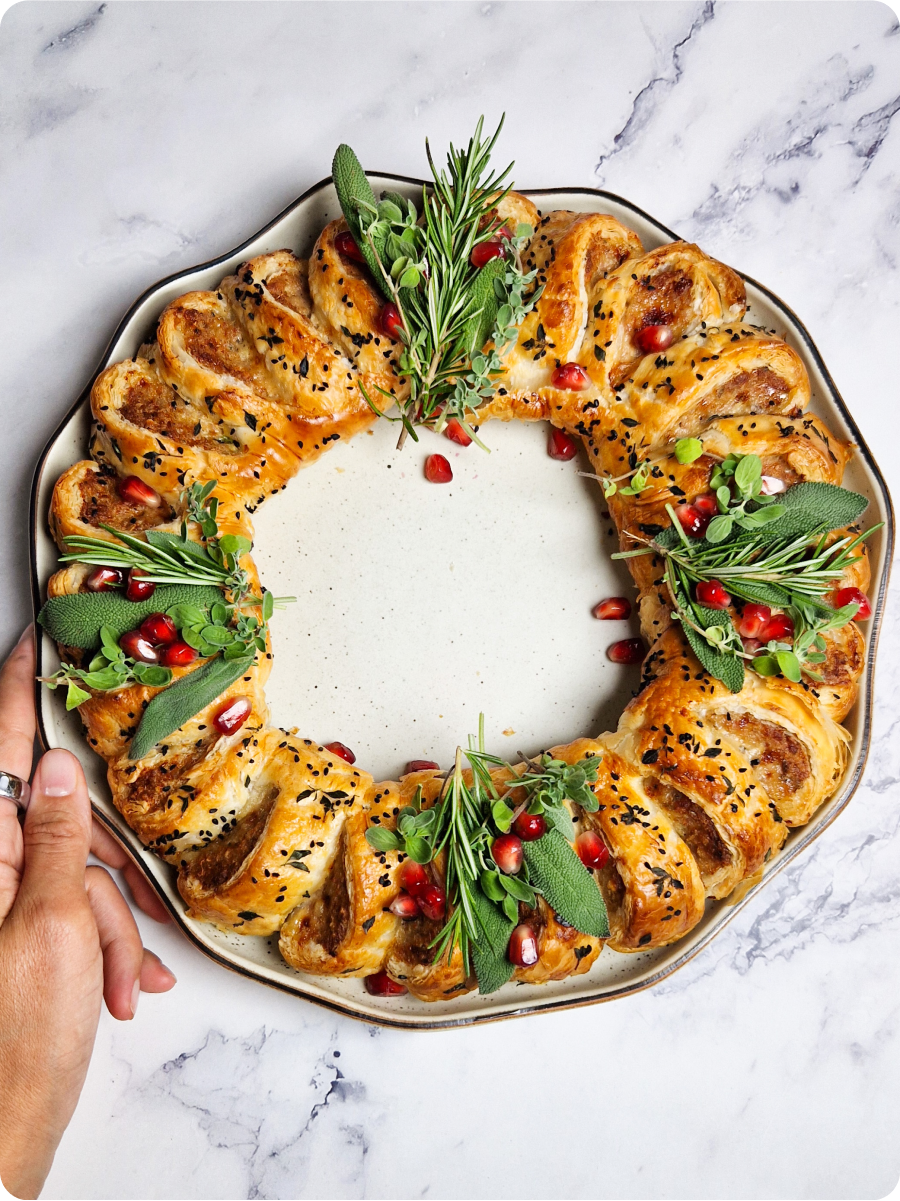 Sausage Roll Wreath after baking. Nice and golden brown and decorated with herbs and pomegranate arils