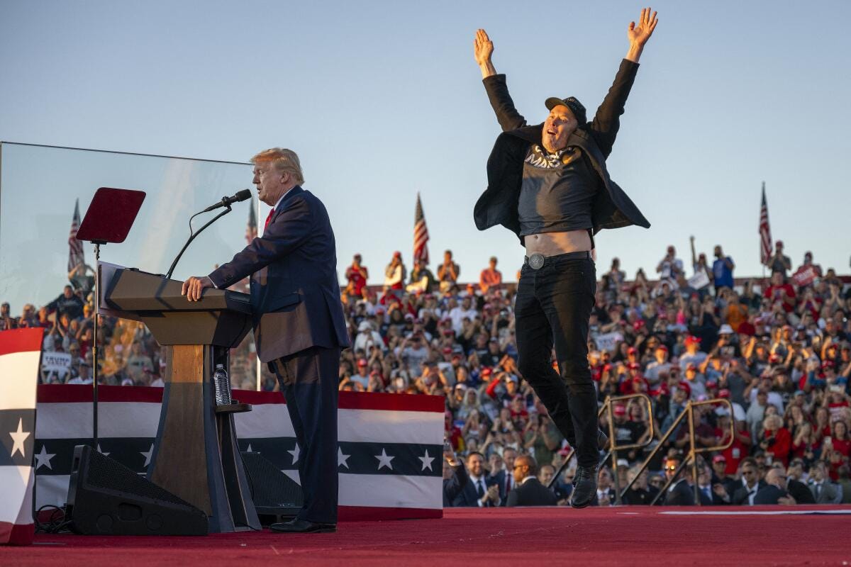 Tesla CEO Elon Musk, right, jumps on stage behind Donald Trump. 