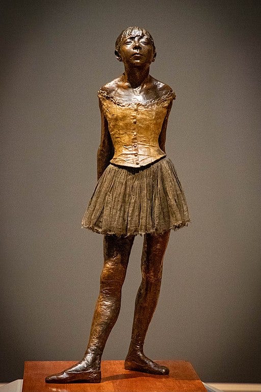 A bronze sculpture of a young ballerina standing with hands clasped behind her, face skyward with closed eyes. She looks exhausted and wears a tattered tutu. A bronze sculpture of a young ballerina standing with hands clasped behind her, face skyward with closed eyes. She looks exhausted and wears a tattered tutu.