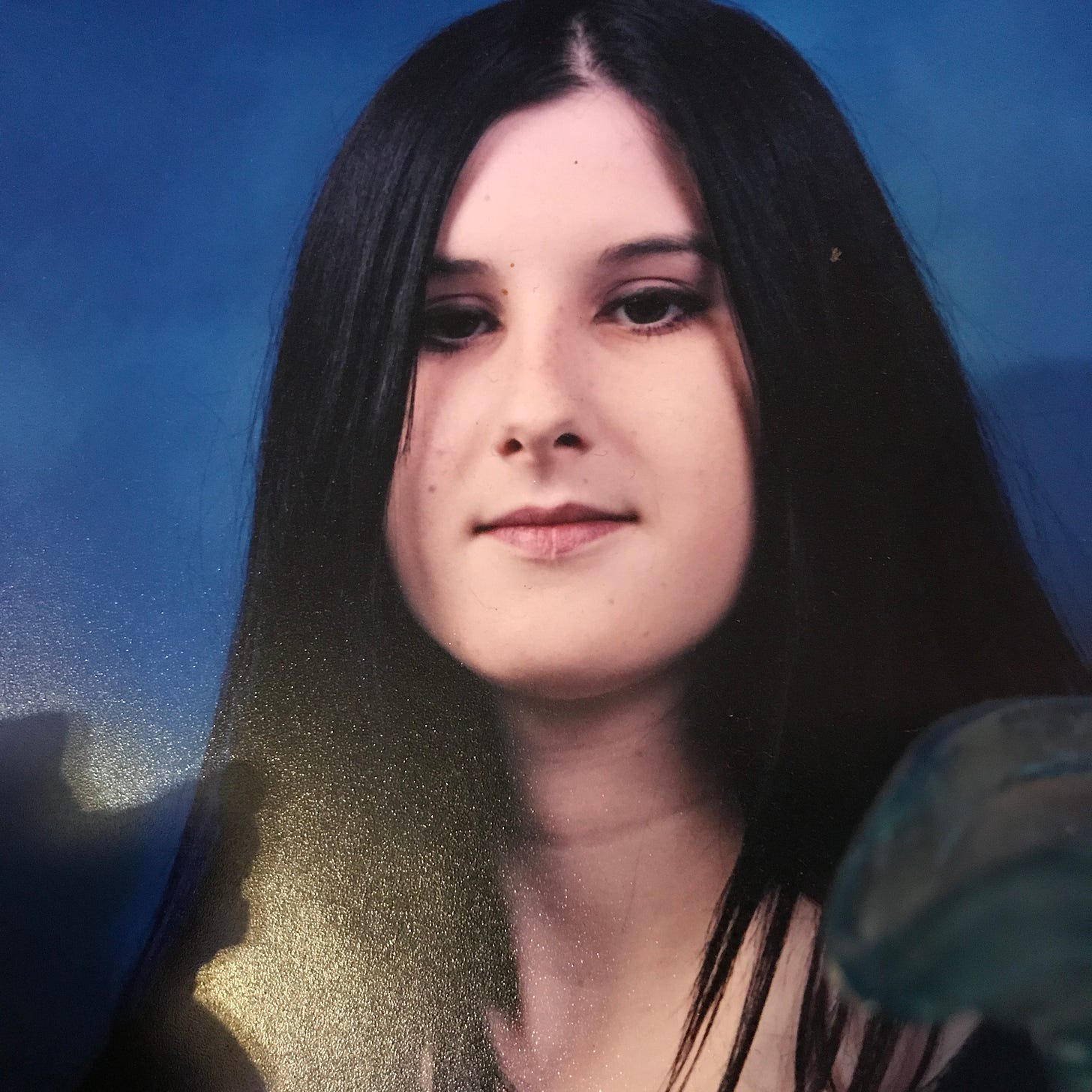 Picture of Lyric in high school with long black hair, and a sullen face. 