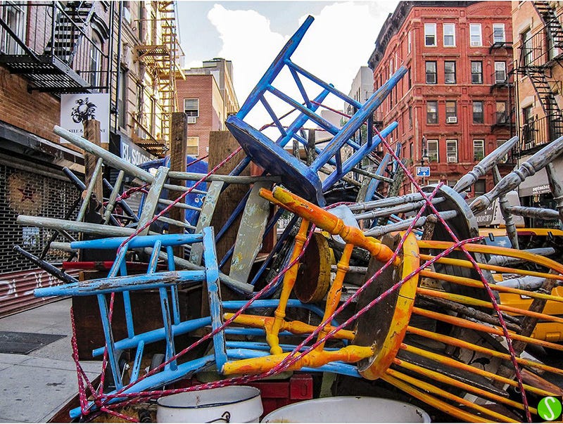photo of a pile of painted wooden chairs tied onto a truck. Ludlow St