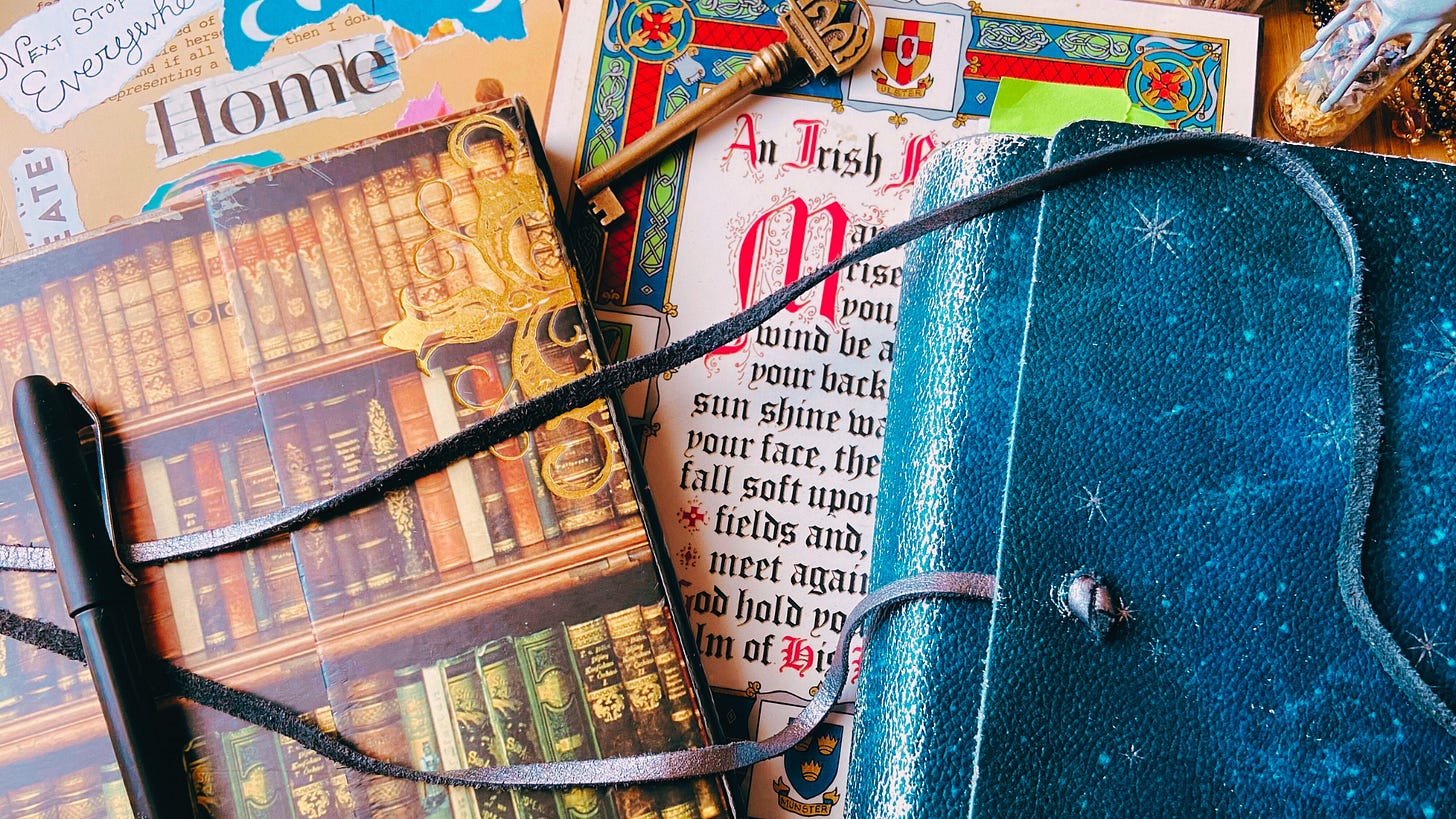 Two colorful journals rest on a desk (one is covered in books, the other in stars) over a copy of a piece of quote art depicting An Irish Blessing.