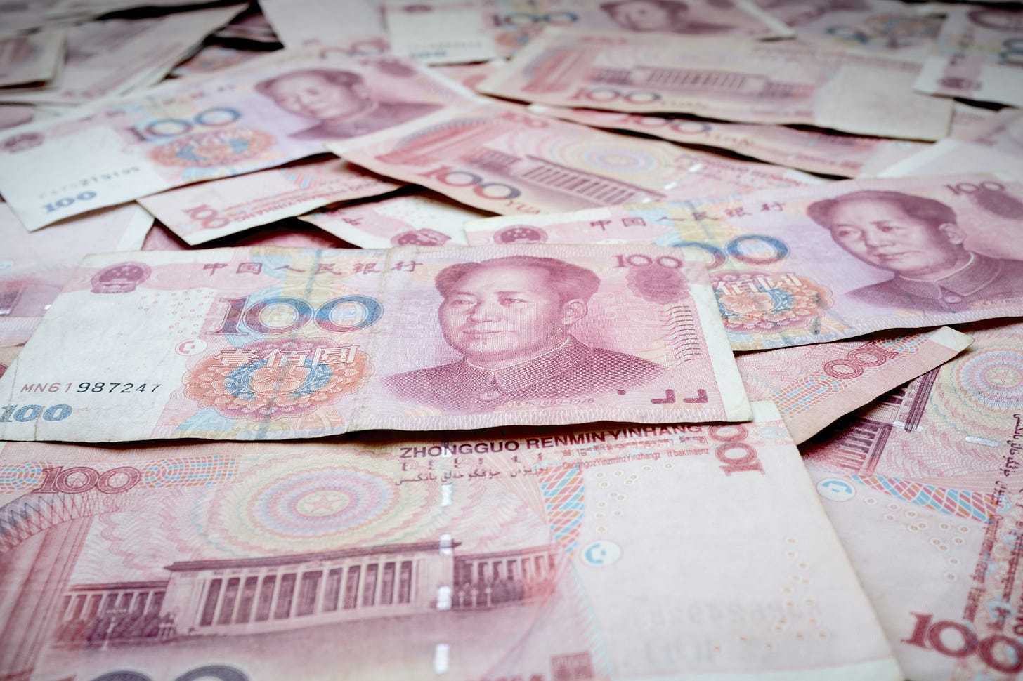 notas de renminbi sobrepostas em coloração avermelhada com uma nota de 100 em destaque no centro com rosto de Mao Zedong notas de renminbi sobrepostas em coloração avermelhada com uma nota de 100 em destaque no centro com rosto de Mao Zedong