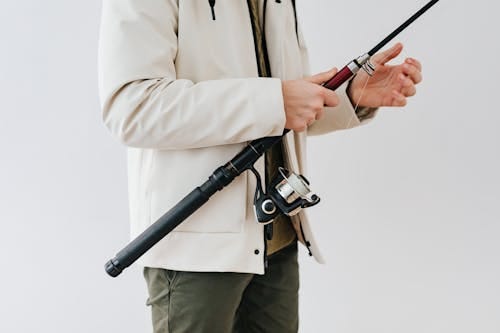 Free Person Wearing White Jacket Holding a Black Fishing Rod Stock Photo