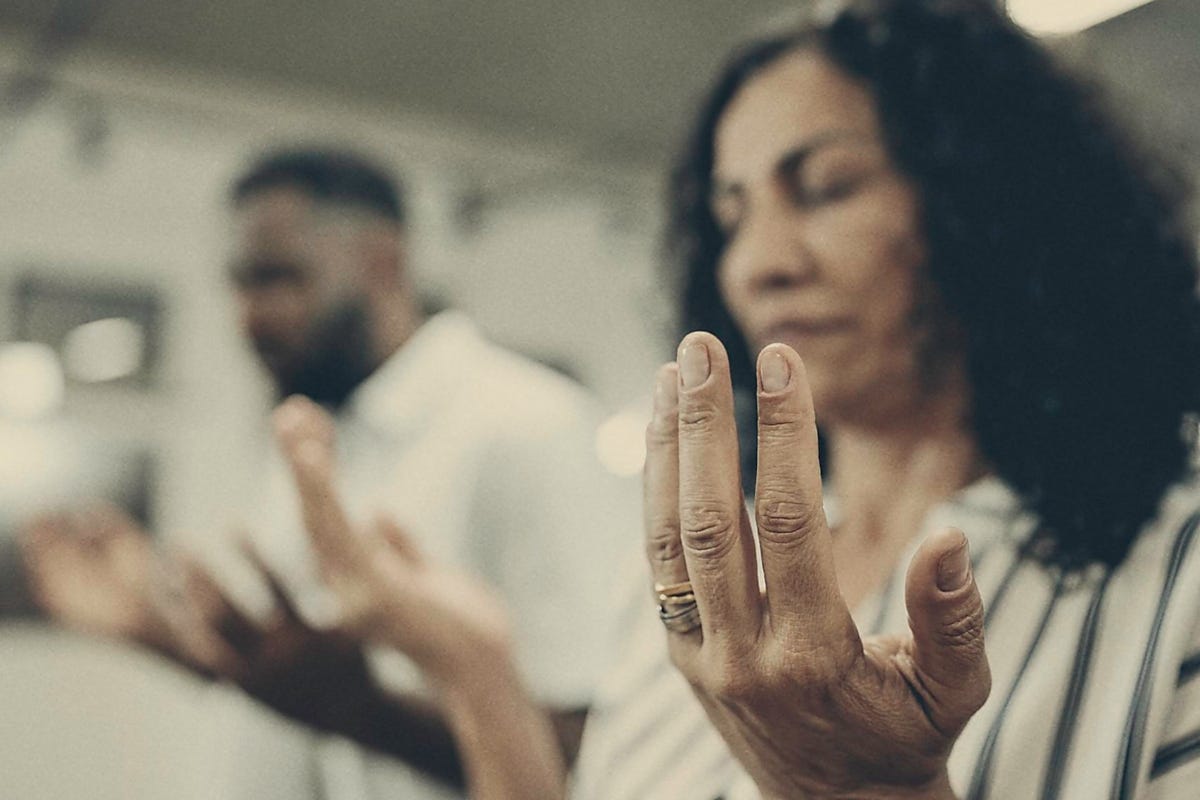 Photo: woman and man praying with hands reaching out