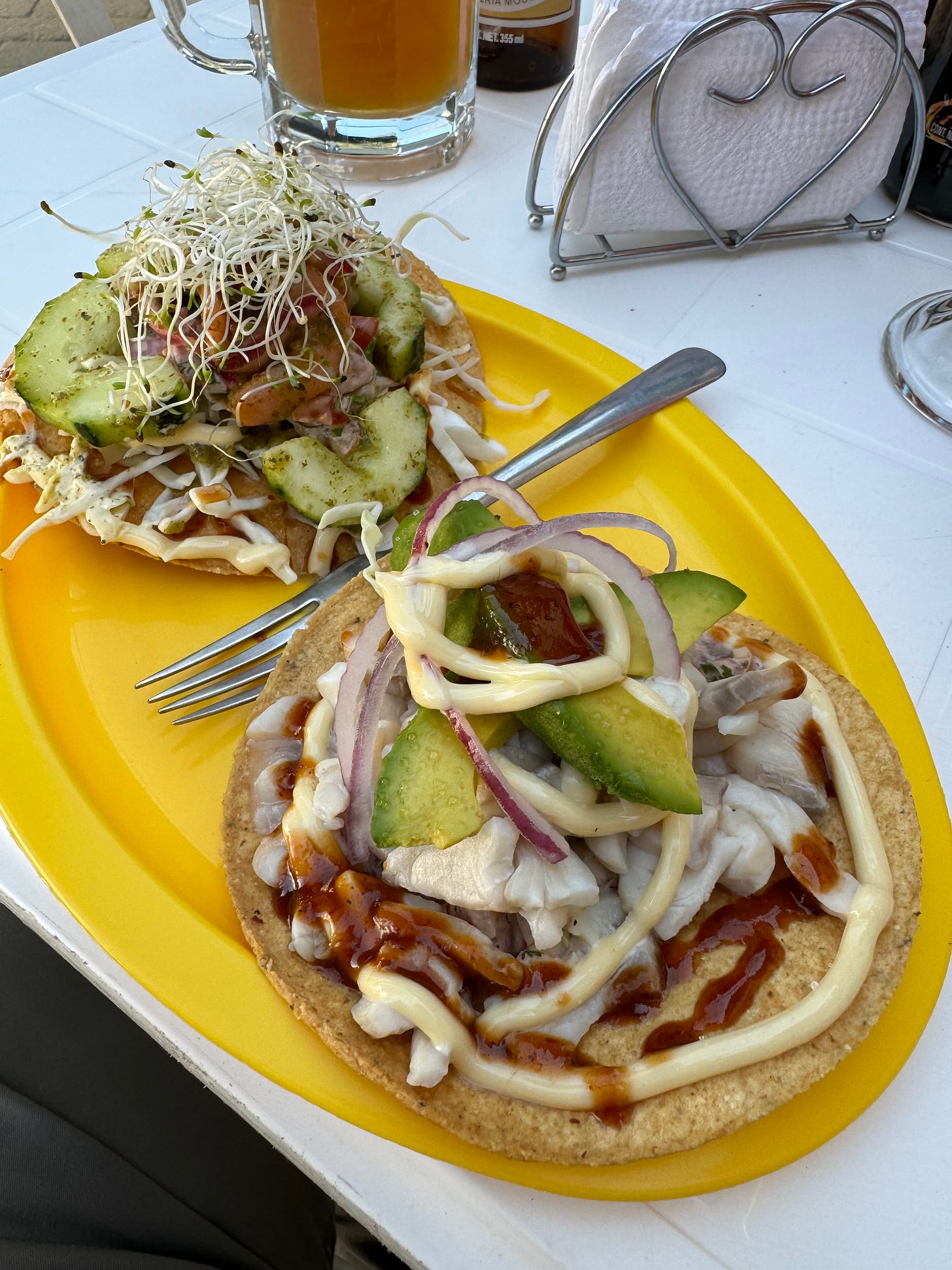 Two seafood topped tostadas on an oval yellow plate.