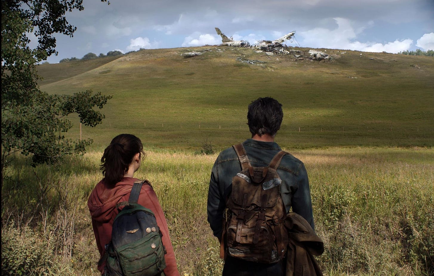 Bella Ramsay and Pedro Pascal as Joel and Ellie in The Last of Us as they look out over the remnants of a plane / HBO