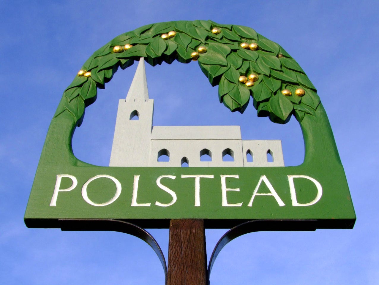 Image of the Polstead village sign set against a blue sky