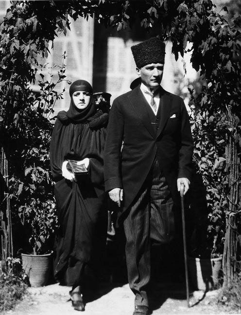 A black and white image of Ataturk and his wife in 1924. Ataturk is wearing a very tall hat. 