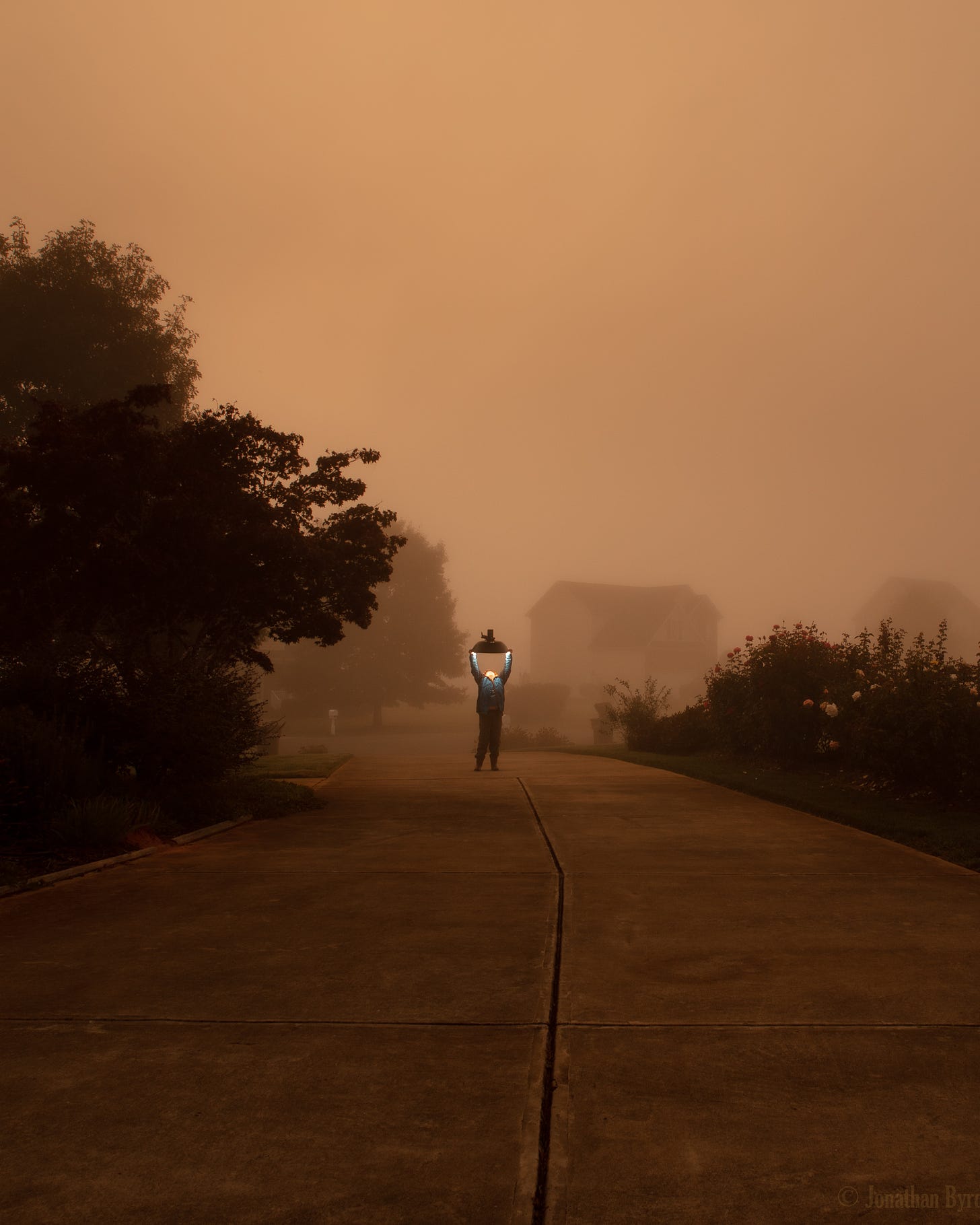 A child holds a light over his head on a foggy day