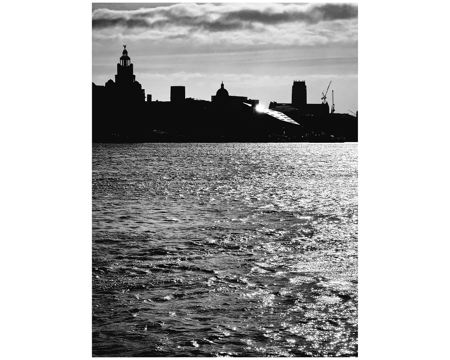 Close up of the Liverpool waterfront in the morning silhoutted against the sunrise. The tide is in.