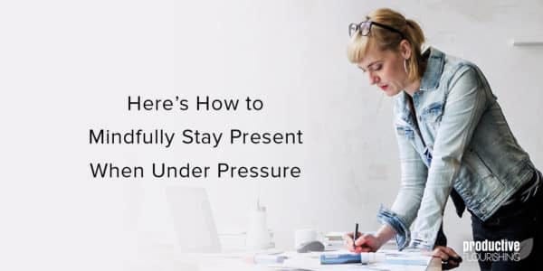 White woman in a denim jacket, standing over a desk. Text overlay: Here's How to Mindfully Stay Present When Under Pressure