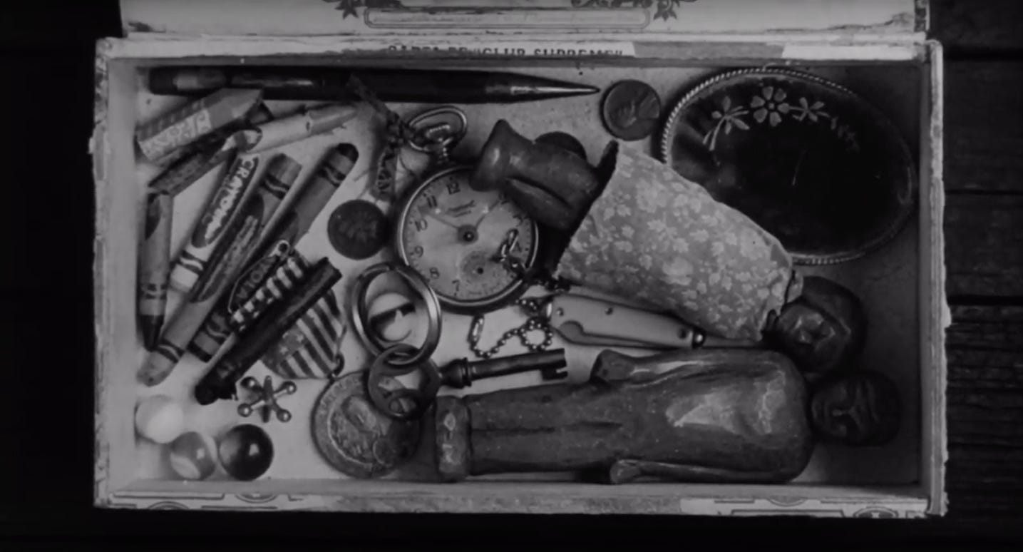 Black and white still from To Kill A Mockingbird showing a child's box of toys and miscellaneous objects.