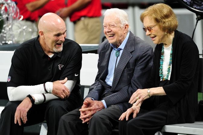 The Carters speak with Atlanta Falcons head coach Dan Quinn prior to an NFL game in September 2018.