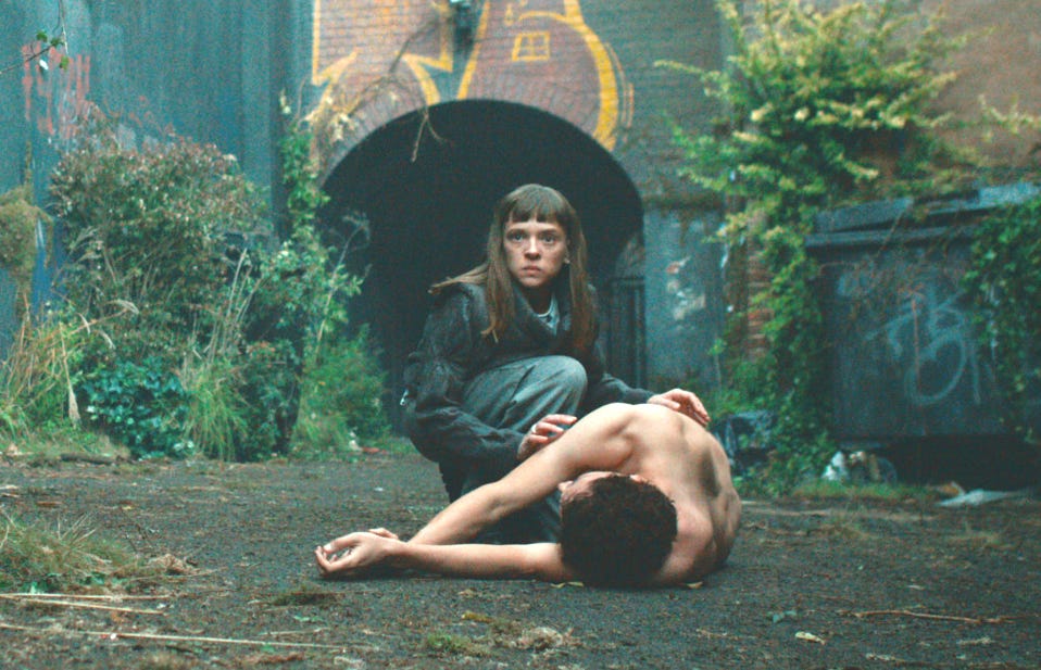 color photograph still of television show "Bodies" showing a woman looking out over a nude body on the ground in an alley