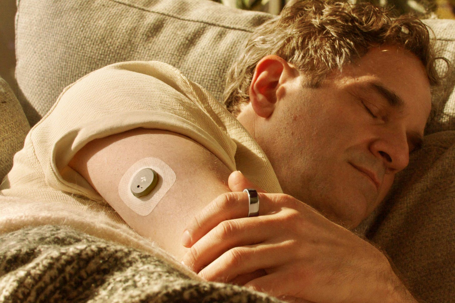 A man sleeping while wearing a Stelo Glucose Biosensor and an Oura Ring