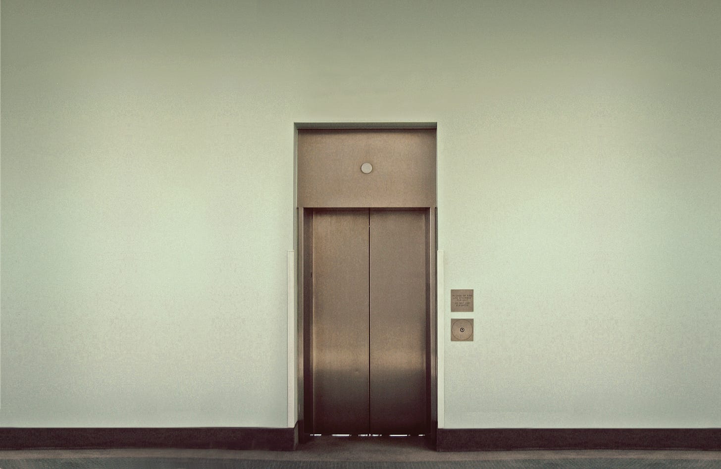 Closed metal doors of an elevator in a large white wall