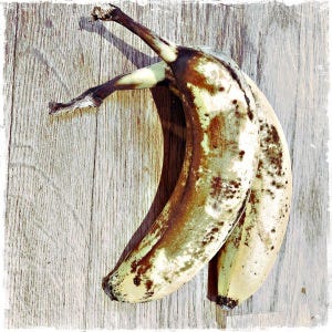 two over ripe bananas sitting on an oak chopping board.