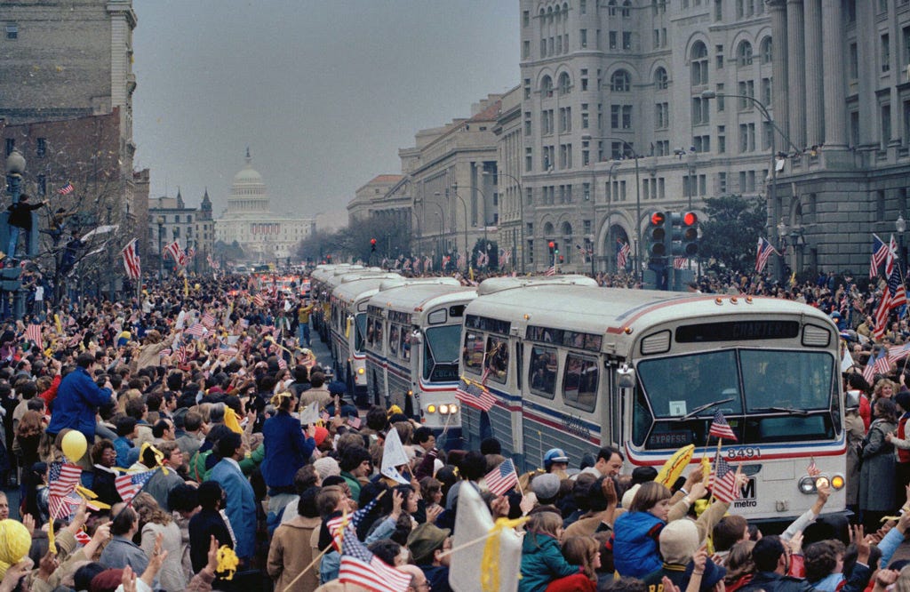 Buses drive through crowds of people with yellow ribbons in Washington, DC
