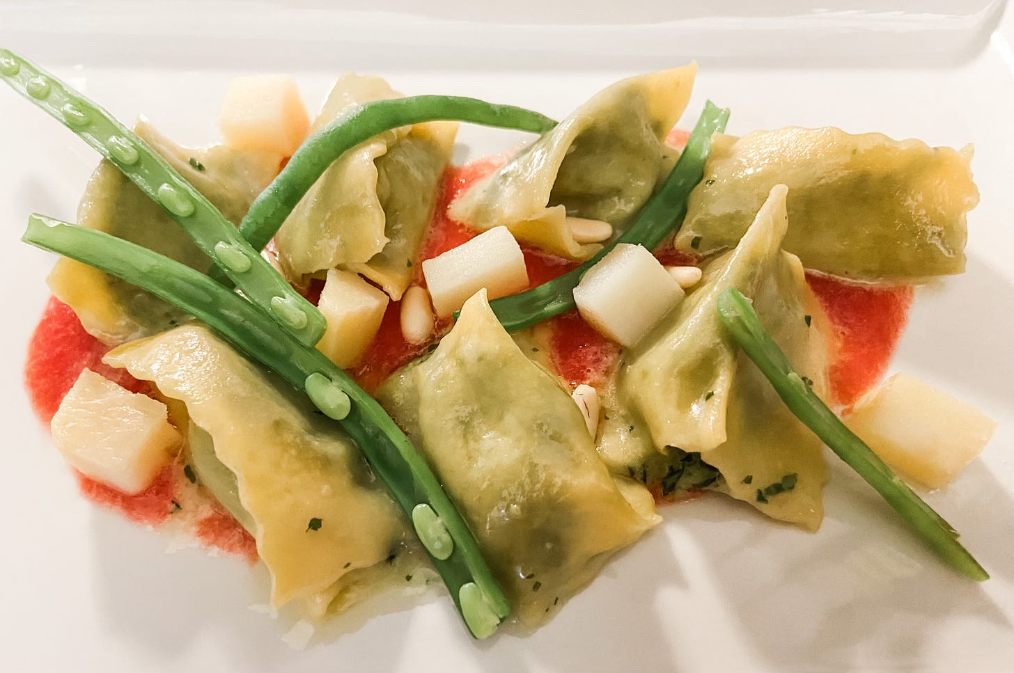 veggie ravioli with beans and tomato sauce on white plate