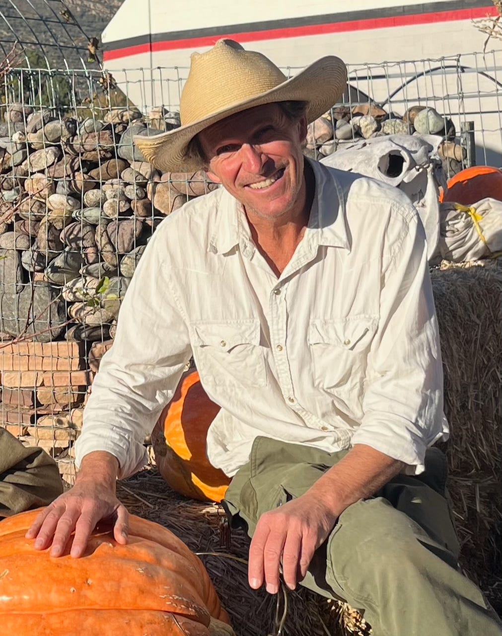 John Taylor sitting next to a 108-pound pumpkin