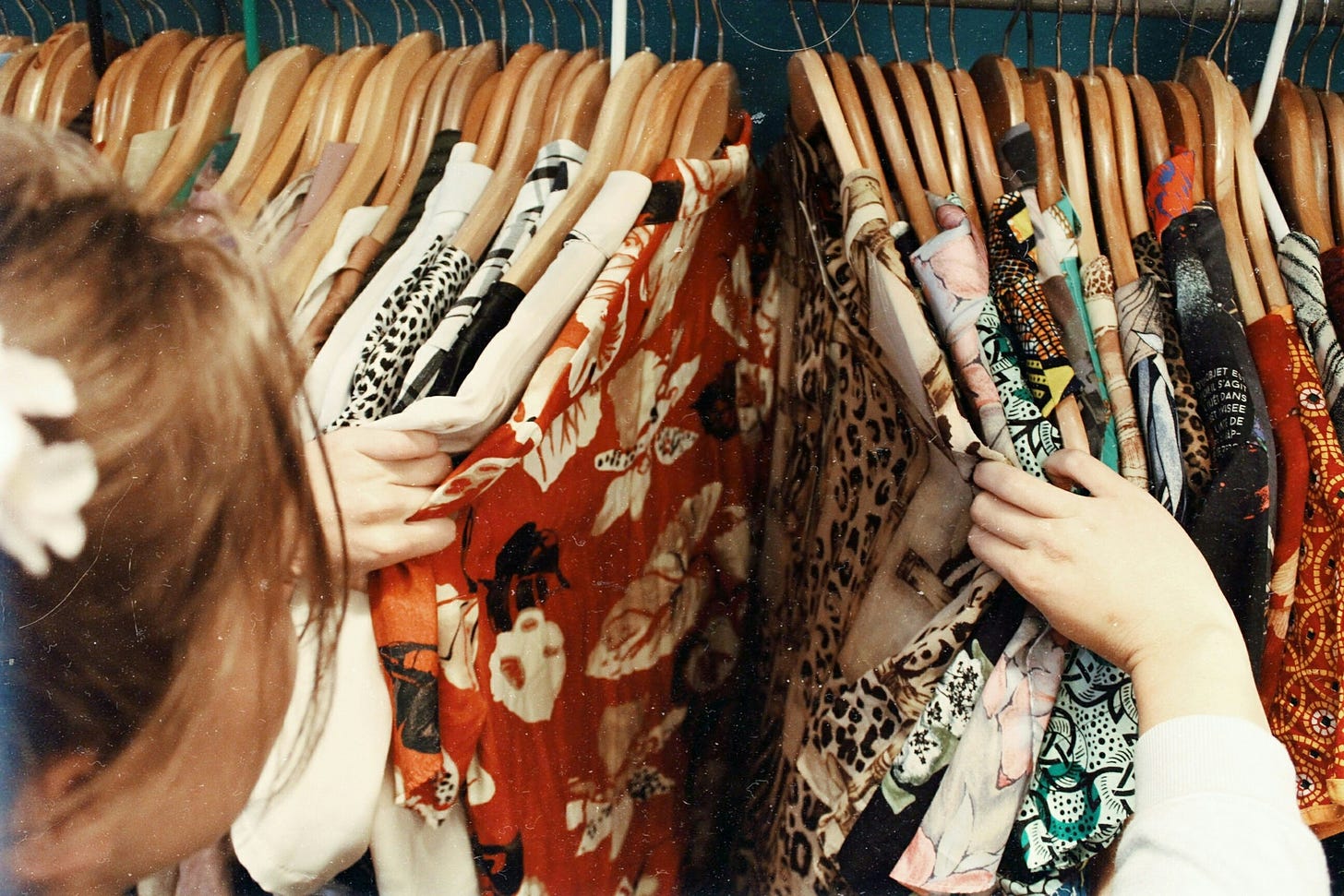 Image of a woman looking into a wardrobe filled with lots of clothes.