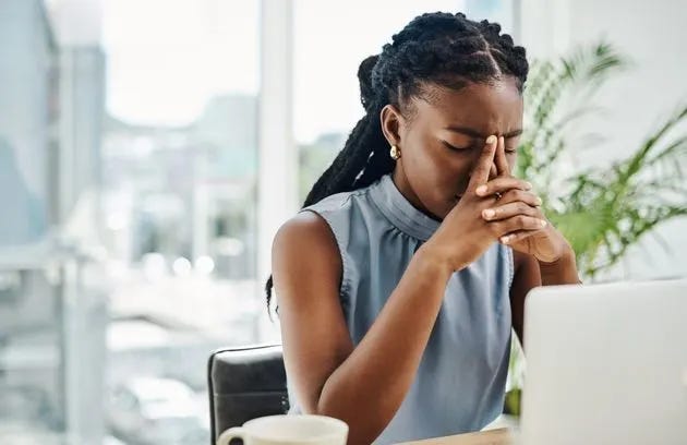 Stressed black businesswoman working on a laptop in an office alone (Photo: Delmaine Donson via Getty Images)