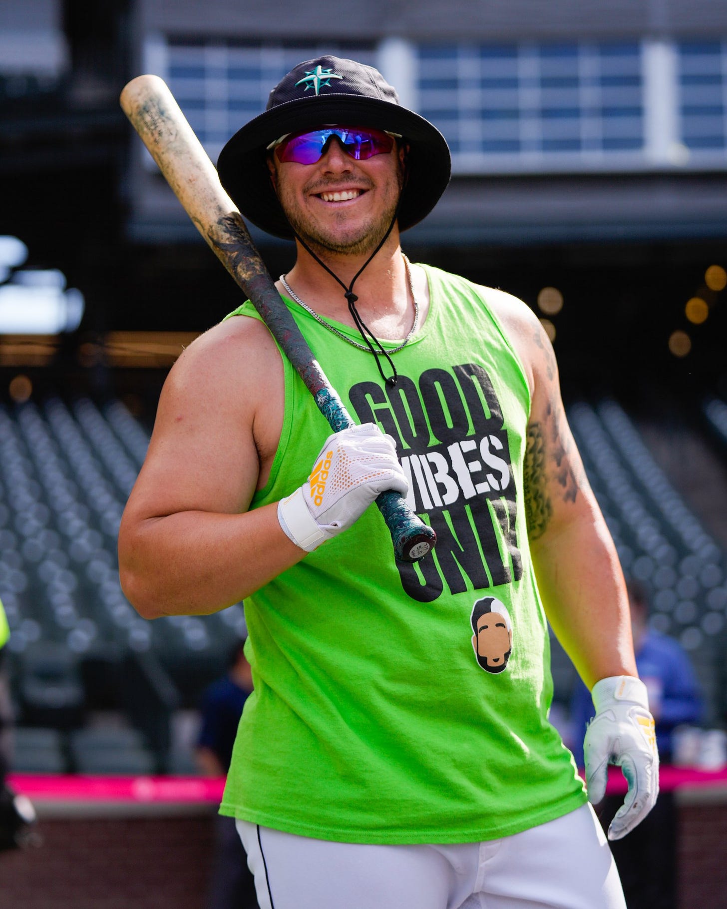 Ty France wears the bright green Eugenio Suárez "Good Vibes Only" tank top and a Mariners bucket hat during batting practice. 
