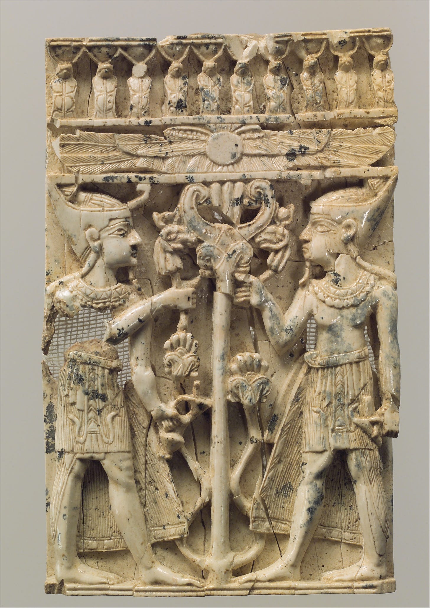 Furniture plaque carved in high relief with two Egyptianizing figures flanking a volute tree, Ivory, Assyrian