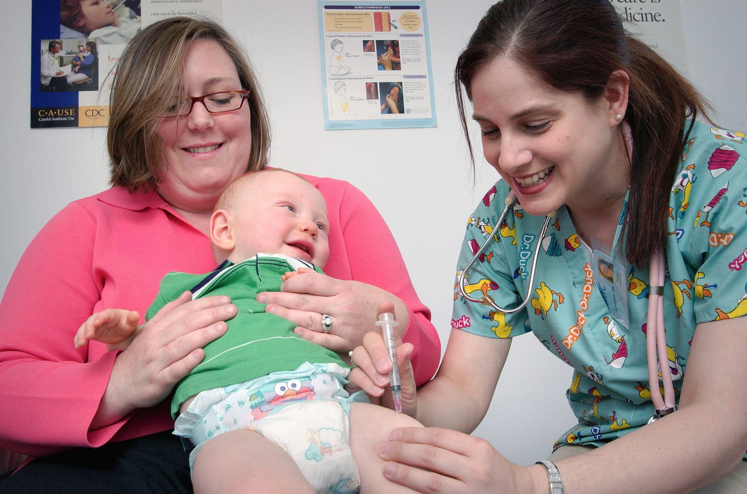 A nurse giving a vaccine to a smiling baby.