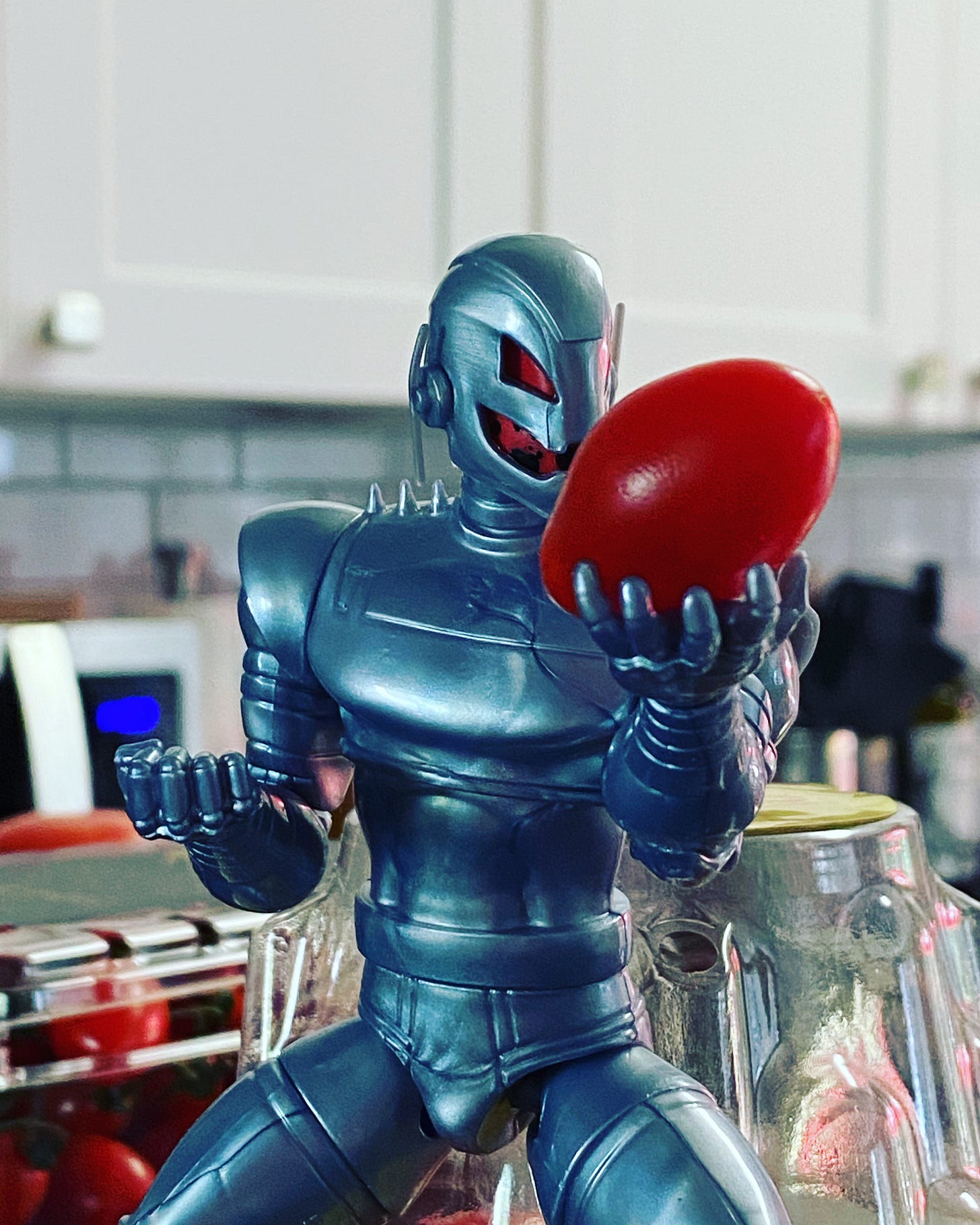 Action figure of Ultron, killer robot, holding a cherry tomato.