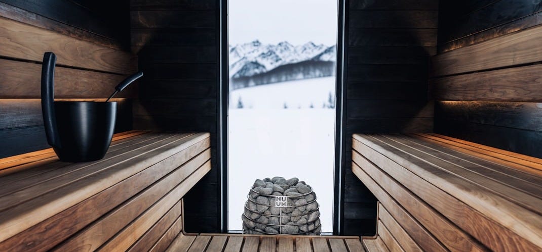 a wooden sauna with a window and a stack of rocks