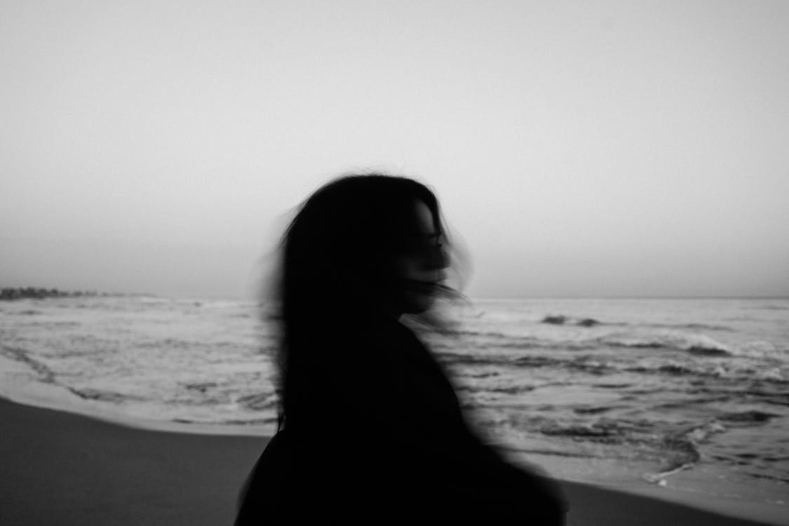 Free Anonymous woman standing on beach Stock Photo