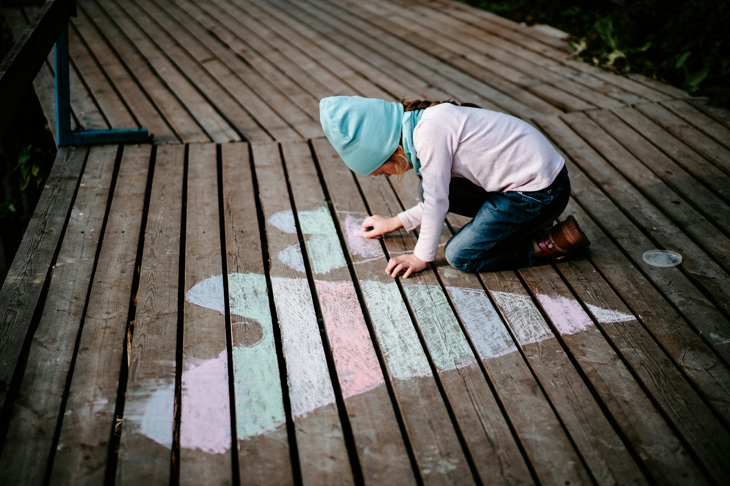 a child drawing chalk hearts on a deck