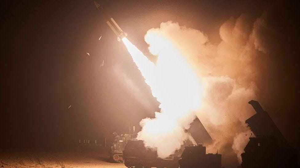 A missile is fired in the night, generating light and smoke.