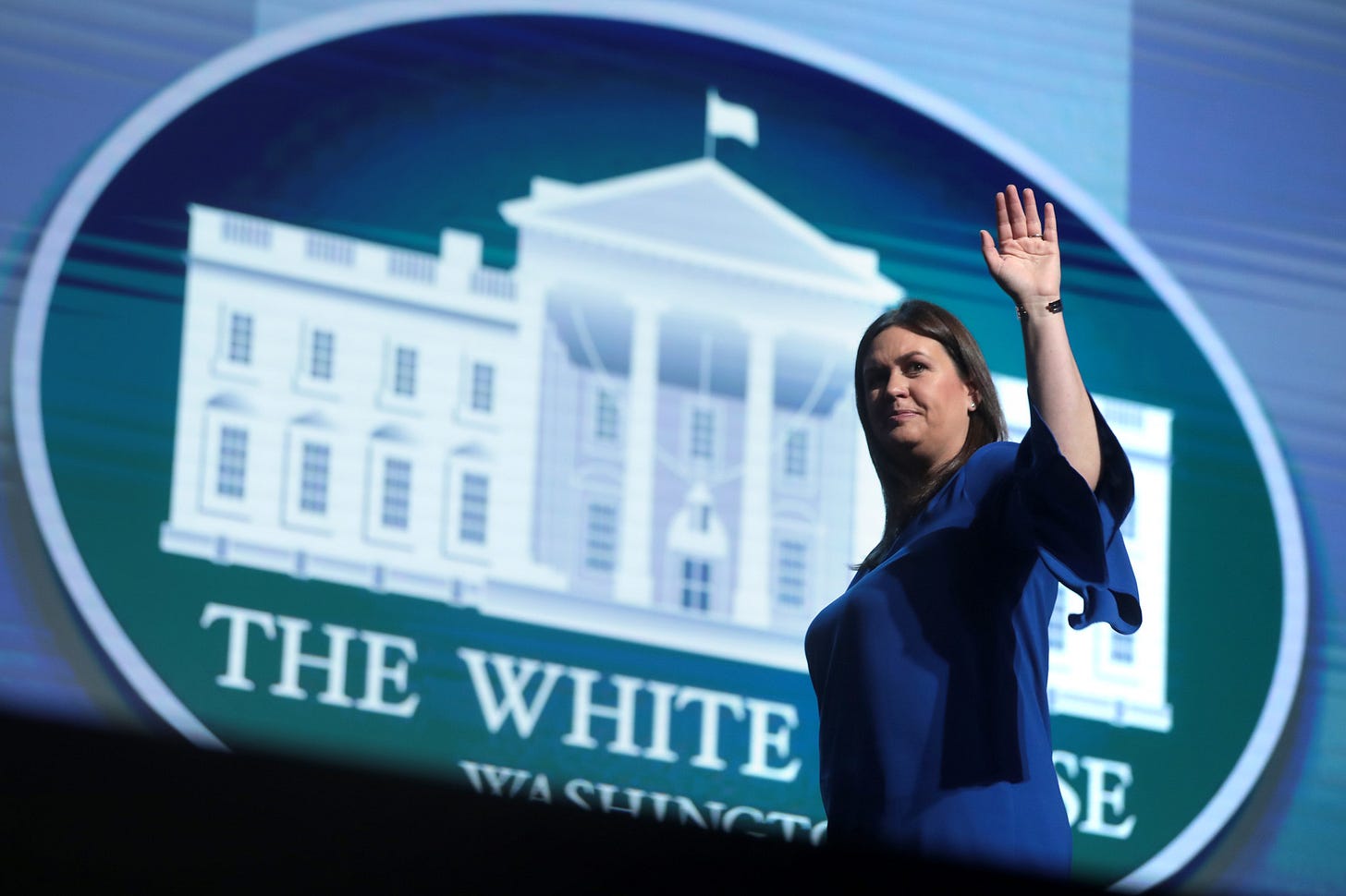 Sarah Sanders in front of a White House logo